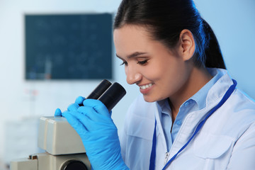 Poster - Female scientist using modern microscope in chemistry laboratory