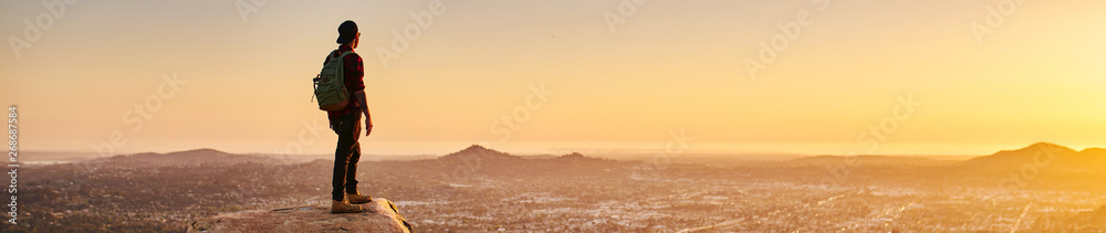 young bearded millennial man hiking on top of hill in california over looking san diego at sunset - obrazy, fototapety, plakaty 