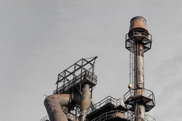 Wall Mural - Smokestack with ladders and catwalks against a grey sky, steel mill, horizontal aspect