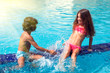 Little boy and girl play in the swimming pool. Children and summer concept