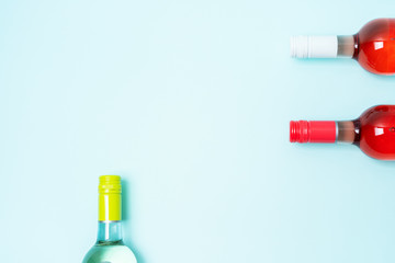 Wall Mural - Layout frame of foil caps in different bright colors of white and rose wine bottles on blue background with copy space. Minimal abstract colorful mockup concept of alcohol beverage. Flat lay.