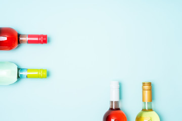 Wall Mural - Mockup frame of bottle foil caps in different bright colors of white and rose wine bottles on blue background with copy space. Minimal abstract colorful mockup concept of alcohol beverage. Flat lay.