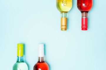 Wall Mural - Layout frame of foil caps in different bright colors of white and rose wine bottles on blue background with copy space. Minimal abstract colorful mockup concept of alcohol beverage. Flat lay.