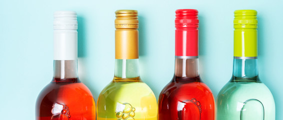Wall Mural - Screw bottle foil caps in different bright colors of white and rose wine bottles on blue background with copy space. Minimal abstract colorful mockup concept of alcohol beverage. Flat lay.