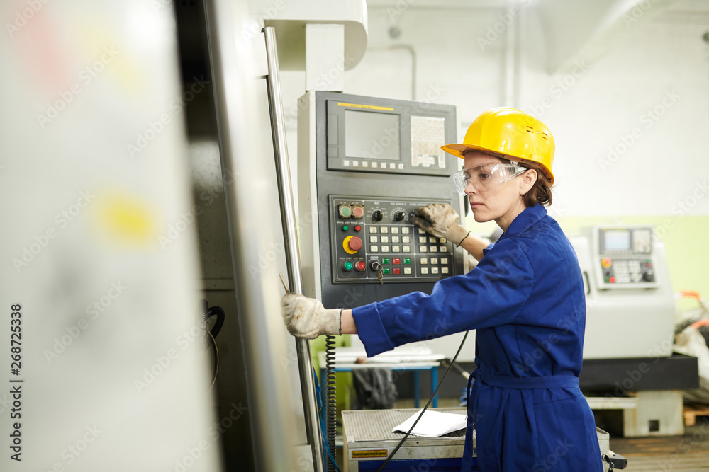 Side view portrait of female worker operating machine units at ...
