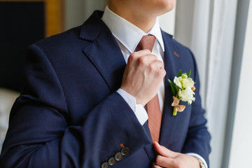 Wall Mural - Elegant businessman sewed to order suit, straightens his tie in an expensive hotel, going to a meeting