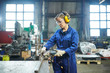 © Seventyfour - Potrait of modern female worker cutting metal at industrial plant or garage, copy space
