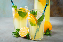 Two Glass With Lemonade Or Mojito Cocktail With Lemon And Mint, Cold Refreshing Drink Or Beverage With Ice On Rustic Blue Background