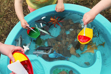 Children Playing With Boats And Sea Creature/Ocean Life Toys In A Water Table. Science/STEM Activity Being Enjoyed By Children In A Daycare/child Care/home School Setting.