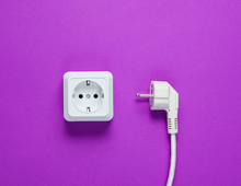 White Plastic Power Socket And Power Plug On Purple Background. Top View