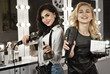 © Ivan - Girls in the beauty salon. Blonde and brunette with tools and cosmetics against background of mirror with backlighting. Masters of manicure and hairdressers are waiting for clients.