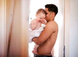 Wall Mural - Father and small toddler son wrapped in towel in a bathroom indoors at home.