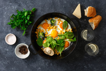 Wall Mural - Breakfast fried eggs frying pan top view on dark stone background