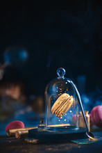 Precious Golden Macaron Cookie Under A Glass Dome. Pastry Art, Conceptual Food Photography With Golden Glitter