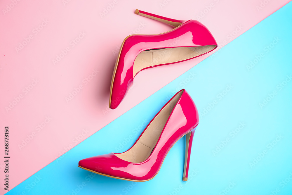 Stylish high heeled shoes on color background