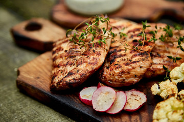 Wall Mural - Grilled turkey meat. Steak turkey grill on wooden cutting board with a variety of grilled vegetables on  rustic background  Top view. Flat lay. Copy space..