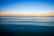 Abstract view of the glassy smooth surface waves of a calm sea during the magic hour of sunrise