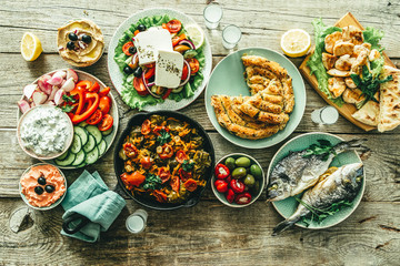 Selection of traditional greek food - salad, meze, pie, fish, tzatziki, dolma on wood background, top view