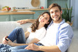 © ty - Portrait of cute young couple sitting in sofa.