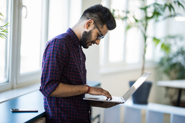 Portrait of Indian man frustrated with work sitting in front of a laptop.