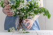 © Andrey Cherkasov - Close-up of woman's hand holding a branch of spring blooming apple tree.Florist concept