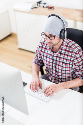Fotomural Computer developer using headphones at work.