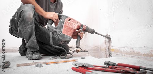 Cuadros en Lienzo Installateur stemmt Loch mit Hilti Bohrhammer in die Wand auf der Baustelle