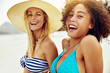 Smiling female friends in bikinis suntanning on a sandy beach
