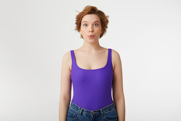 Poster - Portrait of a young happy amazed attractive short-haired girl, wearing a purple jersey, looking at the camera and speaks lips 