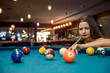 © RomanR - Beautiful woman looking at billiard balls on table