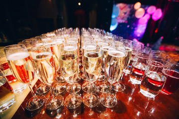 Wall Mural - full glass of champagne in a nightclub. Many glasses of champagne on the bar. bubbles of champagne in a glass.