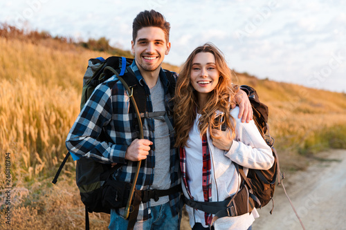 Cheerful young couple carrying backpacks hiking together Tableau sur Toile