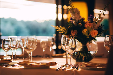 round table with a white tablecloth. the table is decorated with a vase of flowers. wine glass and champagne glass.