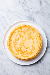 Wall Mural - Crepes, thin pancakes on a white plate. Marble background. Copy cpace. Top view.