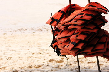 A lot of life jackets hanging on the beach. The concept of water safety.