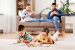 © Syda Productions - family, leisure and people concept - brother and sister lying on floor and drawing in sketchbooks with crayons at home