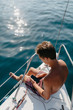 © Boris Jovanovic/Stocksy - Above shot of a teenager using a mobile phone on the sailboat