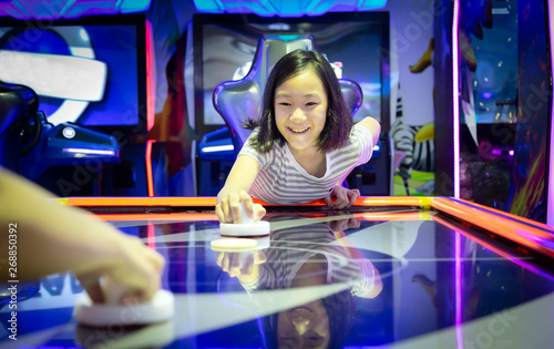 Fotomural Asian little girl playing arcade game on the computer machines at the shopping mall outlets,holiday activities of cute child play games,slot machines in the mall center,vacation concept