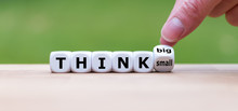 Hand Turns A Dice And Changes The Expression "think Small" To "think Big".