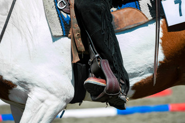 Wall Mural - cowboy leg in a stirrup riding a paint horse detail close up