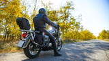 Motorcycle Driver Riding Custom Chopper Bike on Autumn Road. Travel and Adventure Concept.