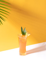 Iced Pineapple Punch Cocktail In Glass On Orange Background. Summer Drink.