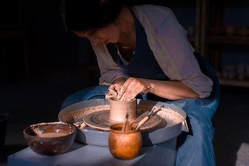 Wall Mural - Charming artisan master making ceramic pot on the pottery wheel . Hand work.