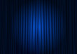 Spotlight on stage curtain. Closed blue curtain background. Theatrical drapes.