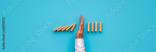 Fotografía Male hand stopping falling dominos