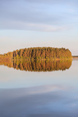 Wall Mural - Amazing windless smooth surface of the lake. Forest in light of setting sun and clouds reflection on calm water. Karelia, Russia. Vertical image