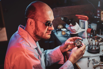 Wall Mural - Smart watchmaker is restoring cutomer's watch at his own repairing studio.