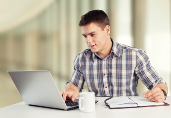 Sticker - Happy young man works on his laptop with coffee at the table