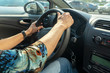 Women's hands hold the steering wheel.
