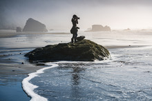 Young Girl On Beach Taking Photos Of Pacific Ocean In Oregon Coast